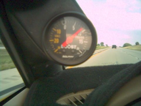 1996 BMW Z3 - A boost gauge is visible on the dashboard of a car driving on a highway, with another vehicle ahead.