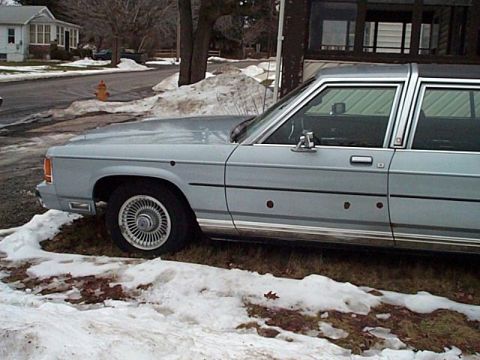 1991 Ford Crown Victoria - This older model Ford sedan, likely from the 1980s, is parked on the side of a road with snow on the ground. Bullet holes are visible on th…