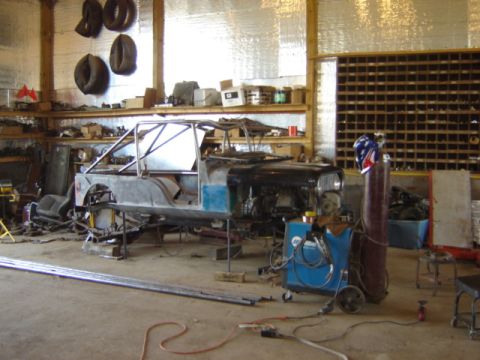 1992 Ford Bronco - A Jeep CJ-5 body is being worked on in a garage, with welding gear and metal stock present.
