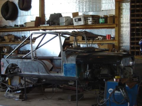 1992 Ford Bronco - A Jeep CJ-6 is being modified with a custom roll cage and metal bodywork in a workshop setting.
