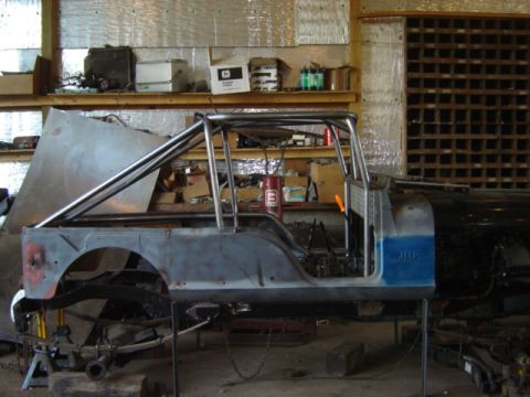 1992 Ford Bronco - A Jeep CJ-6 body is shown in a workshop, undergoing modifications with a prominent roll cage installed.