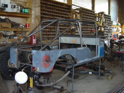 1992 Ford Bronco - Jeep CJ-6 body and frame with a roll cage, being worked on in a garage.