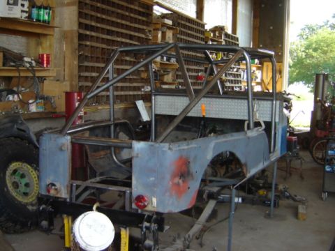 1992 Ford Bronco - A Jeep CJ-5 body is undergoing modifications in a workshop, a newly installed roll cage.