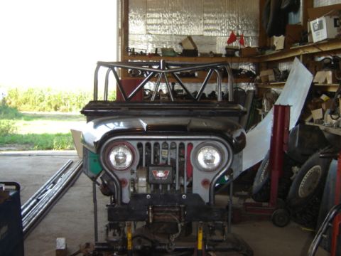 1992 Ford Bronco - A Jeep CJ-6 is seen in a workshop, a custom roll cage and a front-end view.
