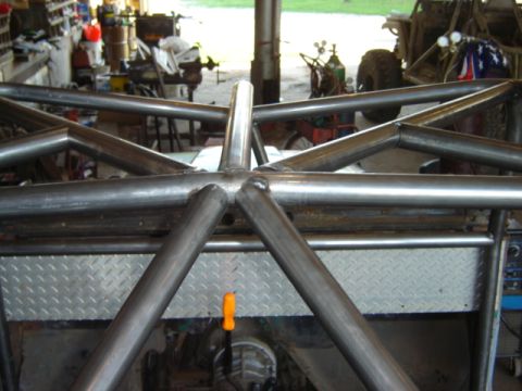 1992 Ford Bronco - A custom roll cage is being constructed or installed in a workshop setting, with tools and other vehicles in the background.