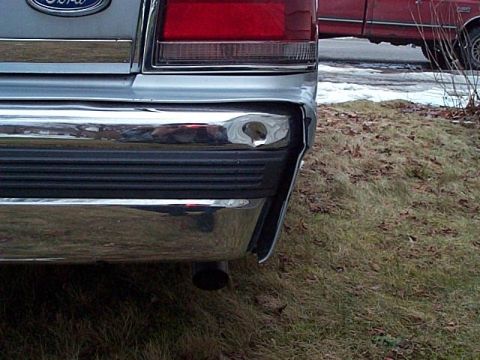 1991 Ford Crown Victoria - The rear of a silver 1990 Ford Crown Victoria is visible, with a red pickup truck in the background.