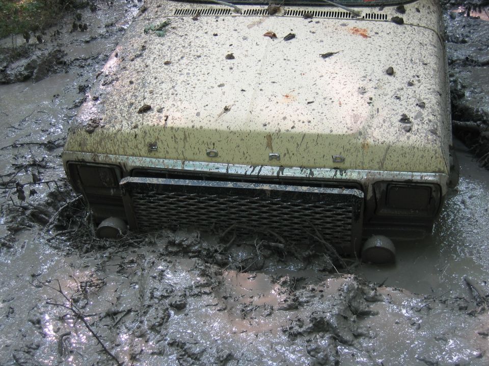 Mud-covered 1979 Ford Mustang front end submerged in thick mud