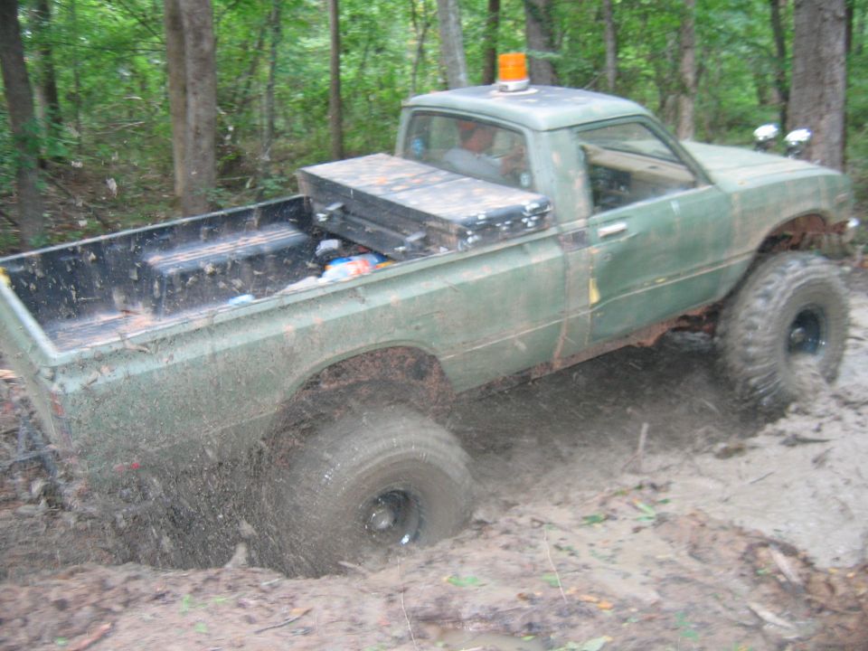 Green pickup truck stuck in mud, side view