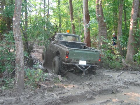 1992 Ford Mustang - Pickup truck navigates a challenging muddy terrain in a forest setting.