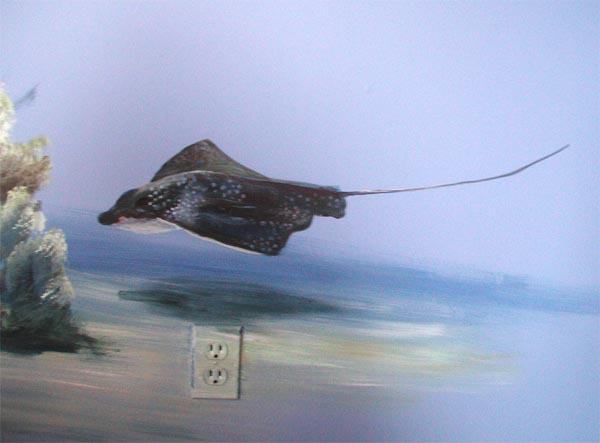 Mural of a spotted eagle ray on a wall with an electrical outlet