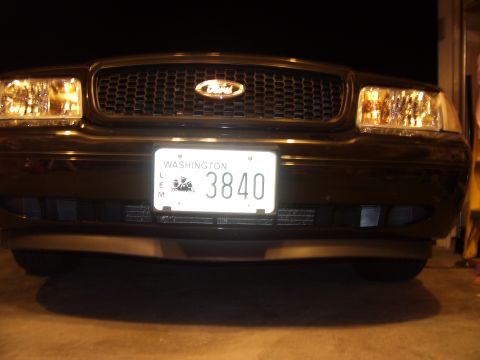 2002 Ford Crown Victoria - The front grille and headlights of a dark sedan are visible, with a Washington state license plate.