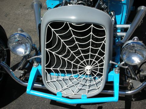 1998 Ford Crown Victoria - custom spiderweb-pattern grille topped with a small skull sits between dual headlights on the front of a light-blue hot rod.