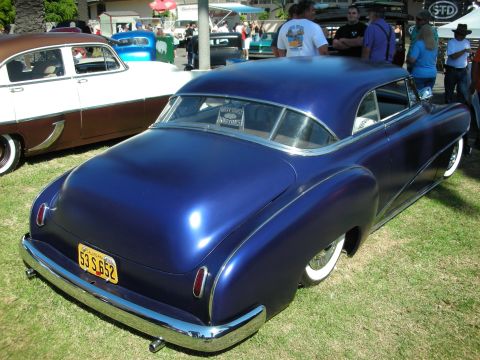 1998 Ford Crown Victoria - metallic deep-blue chopped two-door custom coupe shown from the rear, with whitewall tires and a yellow California license plate, at a car…