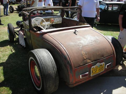 1998 Ford Crown Victoria - weathered patina rat rod roadster seen from the rear, with fat rear tires, open cockpit and a license plate reading KSF 688.