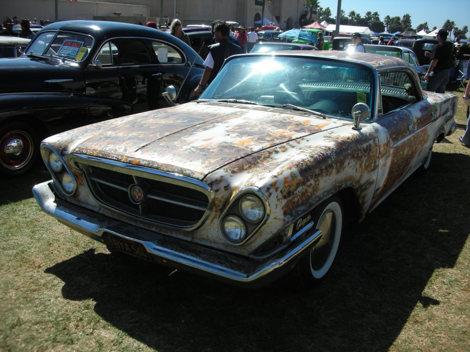Heavily rusted patina early-1960s coupe with whitewall tires at car show