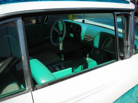 1998 Ford Crown Victoria - View through an open window into a custom car interior with turquoise upholstered seats, a three-spoke wheel and teal-flake roof.