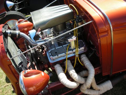 1998 Ford Crown Victoria - copper-orange hot rod's open engine bay showing a chrome-topped V8 with air cleaner, yellow plug wires and heat-wrapped exhaust headers.