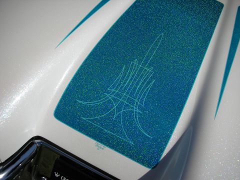 1998 Ford Crown Victoria - Close-up of a teal-blue metalflake scallop outlined by fine pinstriping over white pearl paint on a custom car panel.