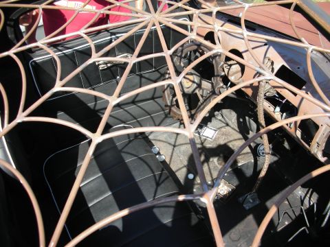 1998 Ford Crown Victoria - Looking down through a fabricated steel spider-web roof into the black interior and dashboard of a custom car.