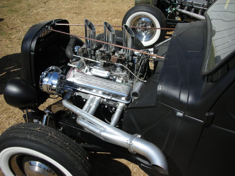 Chrome small-block V8 with multiple carbs and zoomie headers in a black hot rod