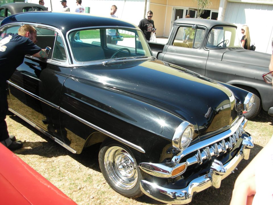 Black 1954 Chevrolet two-door sedan being polished at a car show