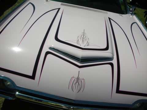 1998 Ford Crown Victoria - Close-up of a white custom car hood featuring a raised scoop, black panel striping and pink-and-black pinstripe artwork.