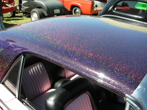 1998 Ford Crown Victoria - Sparkling purple metalflake roof of a custom car above pink and black tuck-and-roll upholstered seats.