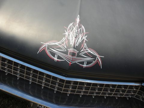 1998 Ford Crown Victoria - Front of a matte black custom car showing intricate red and white pinstripe artwork on the hood above a chrome grille.