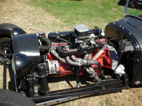 1998 Ford Crown Victoria - Detailed side view of a red and chrome V8 engine with air cleaner and alternator mounted in a low black hot rod.