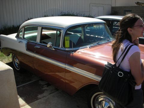 1998 Ford Crown Victoria - Two-tone copper and white mid-1950s Chevrolet four-door sedan parked by a building as a woman with a bag walks past.