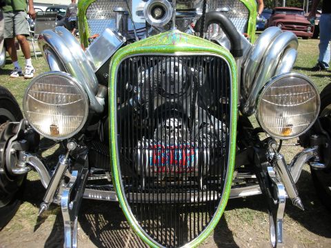 1998 Ford Crown Victoria - Head-on view of a green metalflake hot rod showing its narrow grille shell, dual chrome headlights and exposed engine.