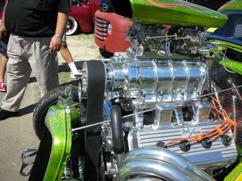 1998 Ford Crown Victoria - Close-up of a polished chrome supercharger and intake on a V8 engine in a green metalflake hot rod with orange plug wires.