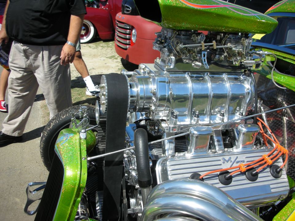 Polished chrome supercharger atop a V8 on a green metalflake hot rod