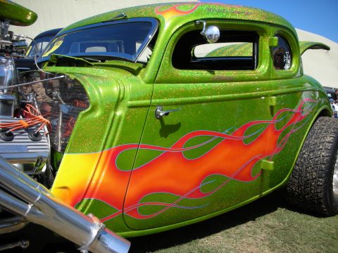 1998 Ford Crown Victoria - Side of a green metalflake hot rod coupe with red and orange flame paint, chopped top and exposed chrome engine.