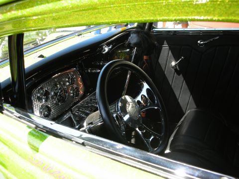 1998 Ford Crown Victoria - Through-the-window view of a custom car's black interior featuring a chrome steering wheel, engine-turned dash insert and tuck-and-roll doo…