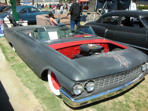 1998 Ford Crown Victoria - satin-black lowered convertible with its hood up showing a red-painted engine bay and pinstriping, displayed on grass at a car show.