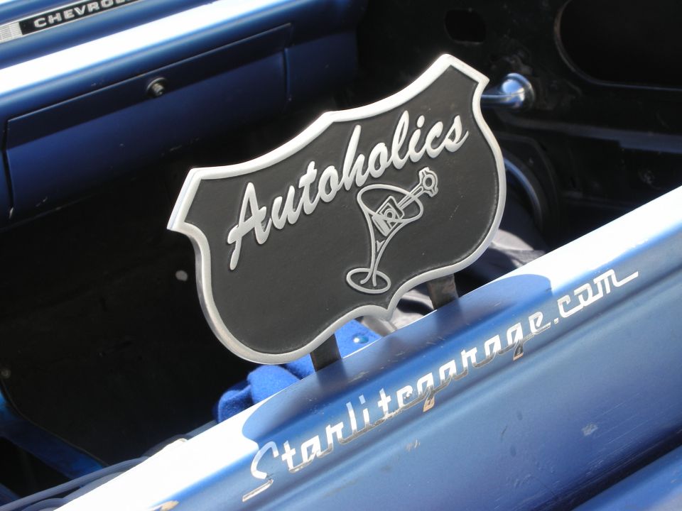 Black and chrome Autoholics club plaque mounted on a blue car, Starlitegarage.com text