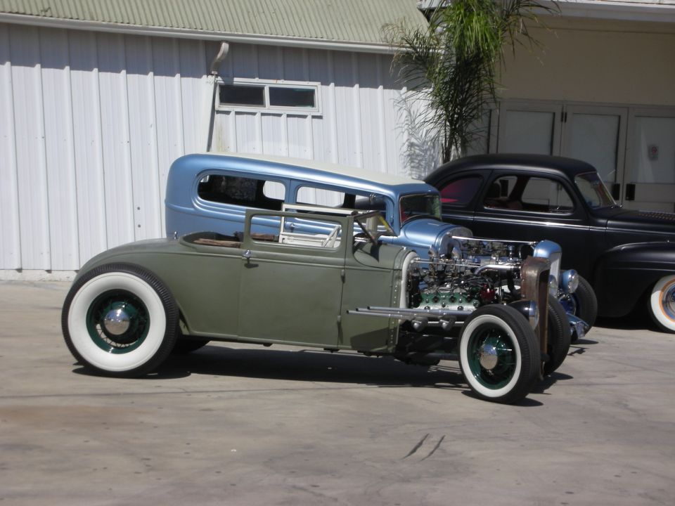 Chopped low green-and-blue sedan hot rod with exposed chrome V8 and whitewall tires