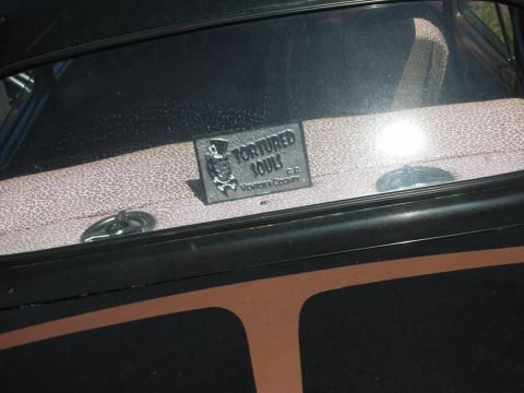1998 Ford Crown Victoria - small Tortured Souls Ventura County car-club plaque sits in the rear window above a brown-and-black pinstriped deck.