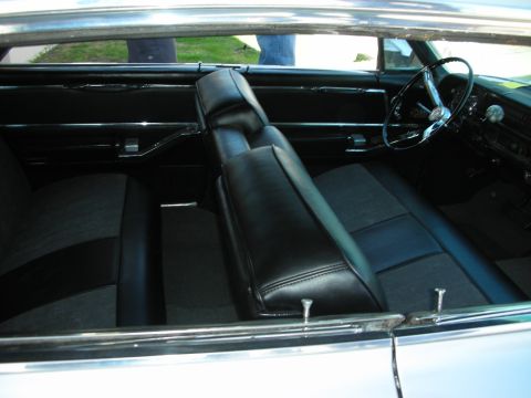 1998 Ford Crown Victoria - black bench-seat interior, dashboard and steering wheel of a vintage car viewed through an open side window.