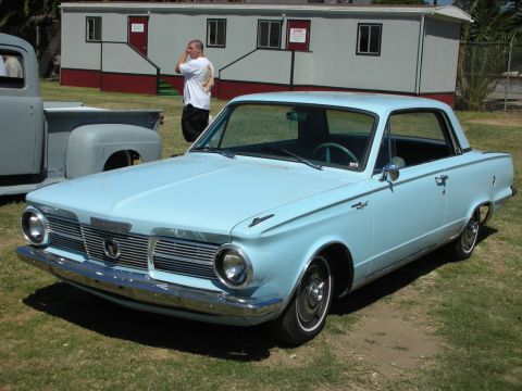 1998 Ford Crown Victoria - light-blue mid-1960s Plymouth Valiant two-door compact parked on grass in front of a portable building.