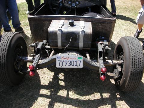 1998 Ford Crown Victoria - rear of a rat rod shows the exposed frame, a metal fuel tank and round taillights, with California plate 7Y93017.