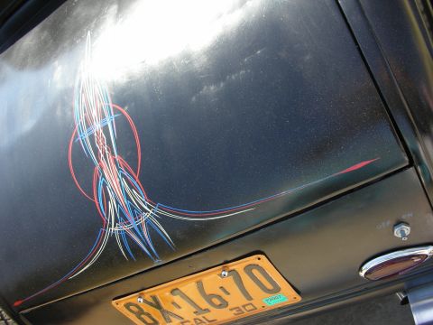 1998 Ford Crown Victoria - Intricate red, white and blue pinstriping decorates the black trunk lid of a hot rod, next to a vintage yellow California plate reading 8X1…