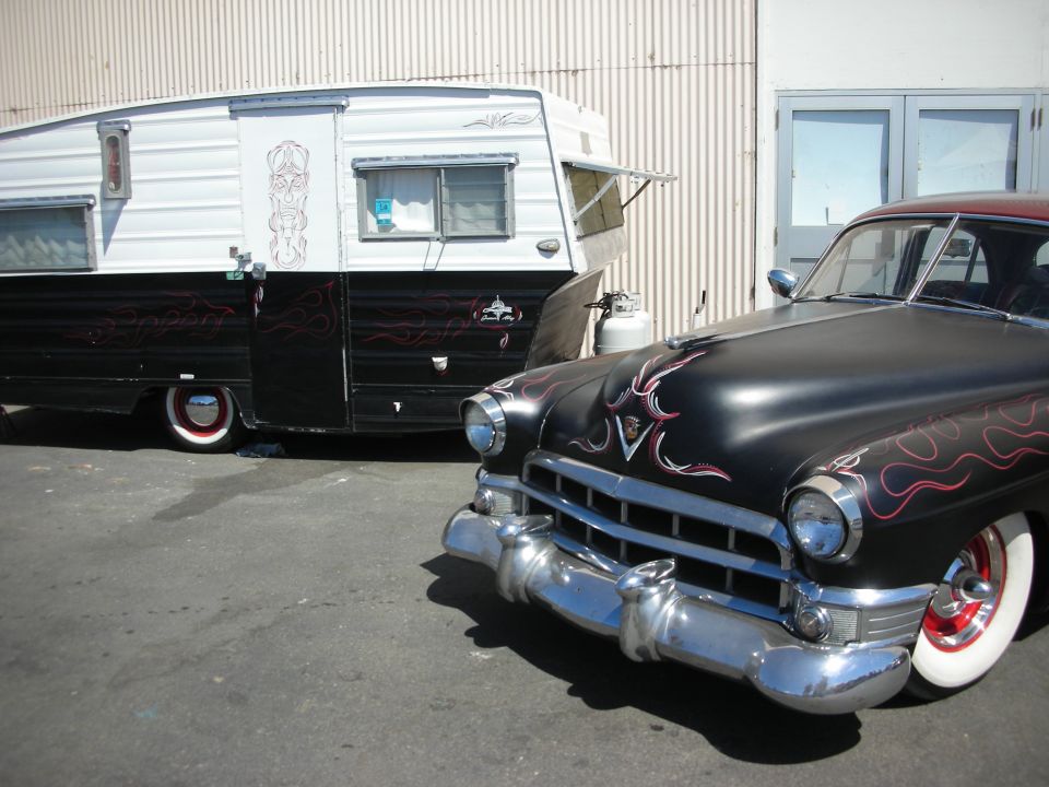 Black flamed 1940s Cadillac next to matching pinstriped vintage travel trailer