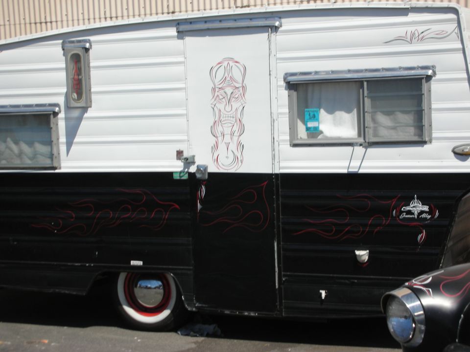 Black-and-white vintage travel trailer with red pinstriping and tiki-style art