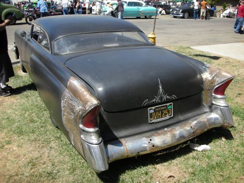 1998 Ford Crown Victoria - Rear three-quarter view of a flat-black chopped custom car with tailfins, pinstriping and a yellow California plate JVH 253.