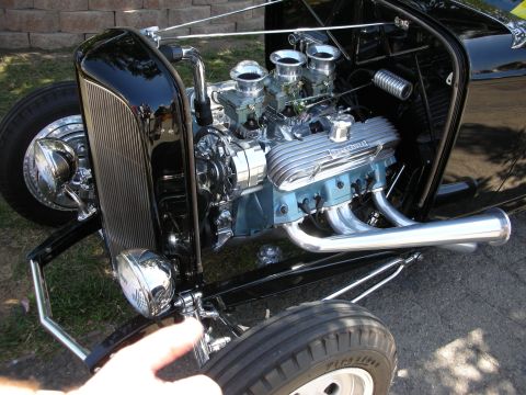 1998 Ford Crown Victoria - polished V8 engine with dual carburetors and chrome headers sits exposed in the engine bay of a black hot rod roadster.