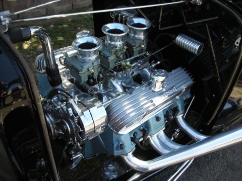 1998 Ford Crown Victoria - Detailed close-up of a polished aluminum finned V8 engine fitted with chrome carburetors and tubular headers.