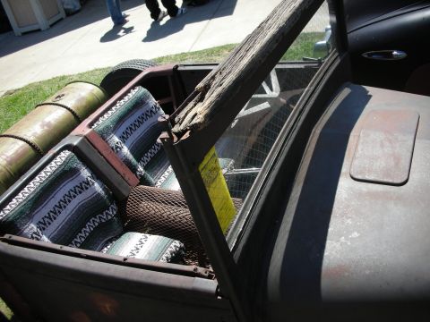 1998 Ford Crown Victoria - open rumble-seat area of a rat rod fitted with a striped Mexican-blanket cushion, weathered wood trim and mesh detailing.