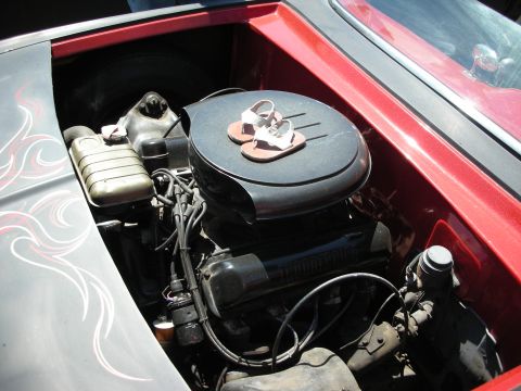 1998 Ford Crown Victoria - Open engine bay of a red custom car showing a V8 with oil-bath air cleaner and white-flame pinstriping on the inner fender.